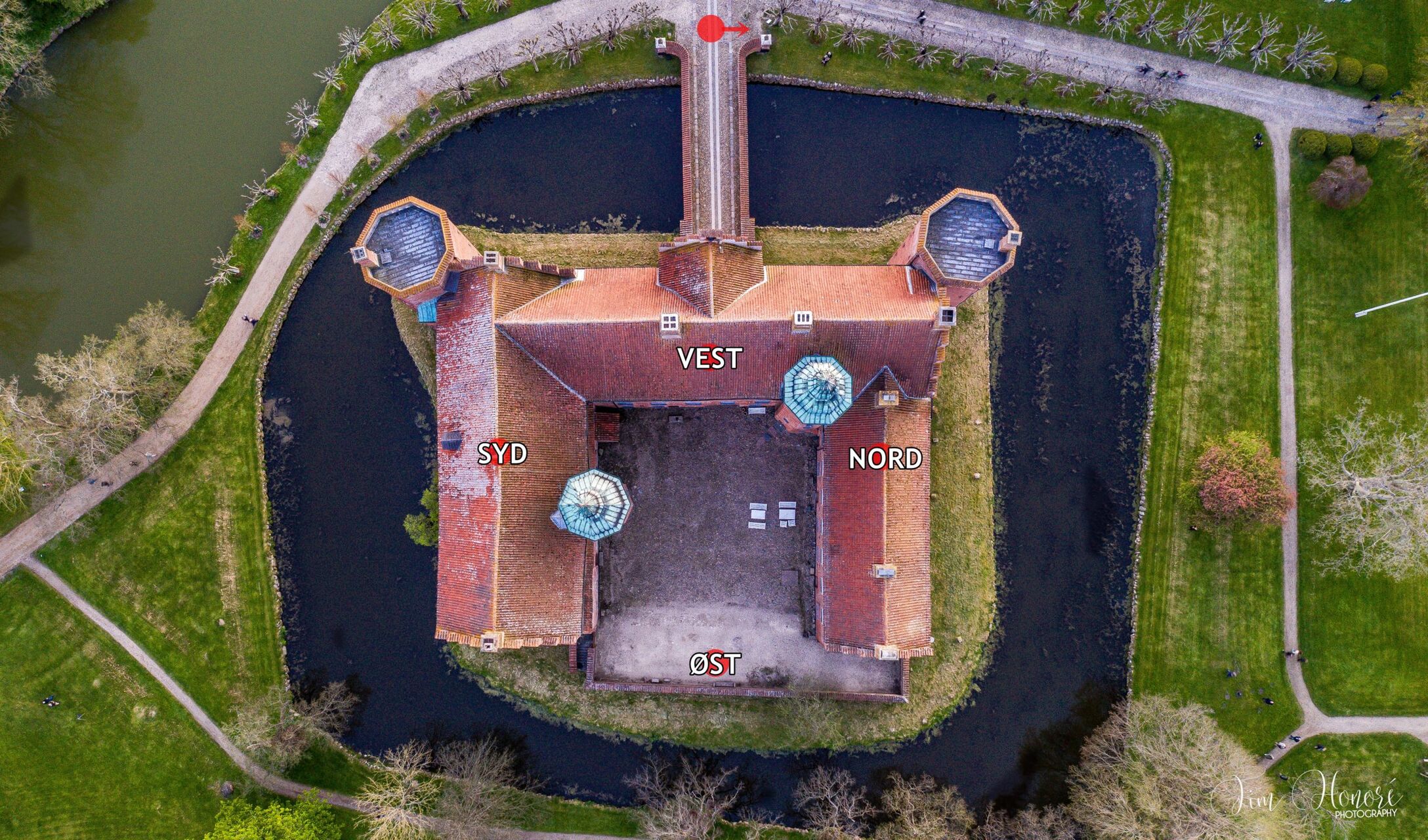 Orangerierne og barokhaven på Gammel Estrup i tusmørke med lys langs stierne